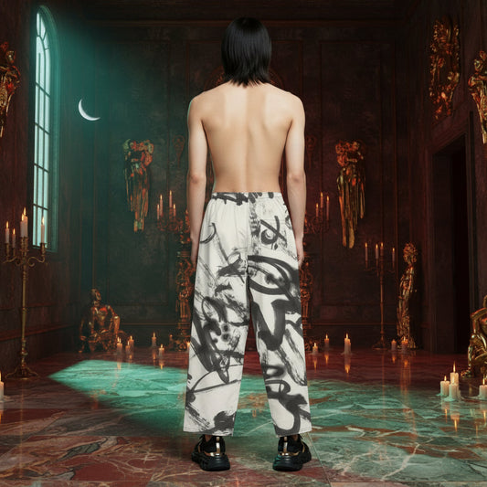 A person stands with their back to the camera in a dark, candle-lit room, wearing loose white trousers with a bold black abstract brushstroke pattern and black shoes.