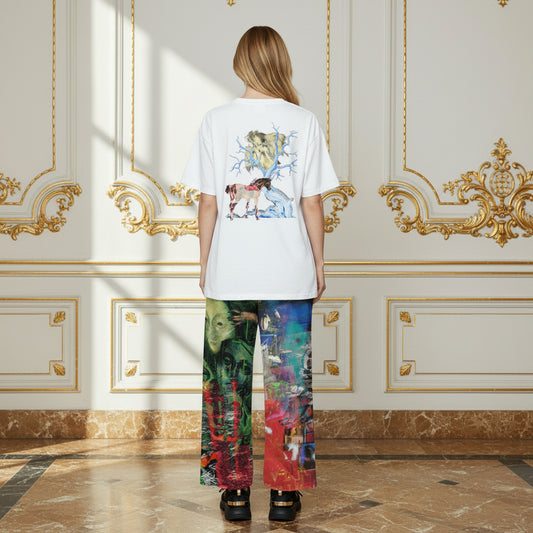 A model viewed from behind wearing a white t-shirt with a colorful graphic print on the back and matching multicolor patterned wide-leg pants, standing in a luxurious room with gold-trimmed cream walls and marble floors.