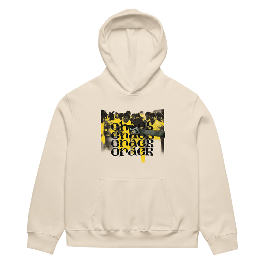A cream-colored pullover hoodie with a front kangaroo pocket and a central graphic print featuring a black-and-white crowd scene with bold yellow and black text reading 'ONE CHARGE ORDER'.